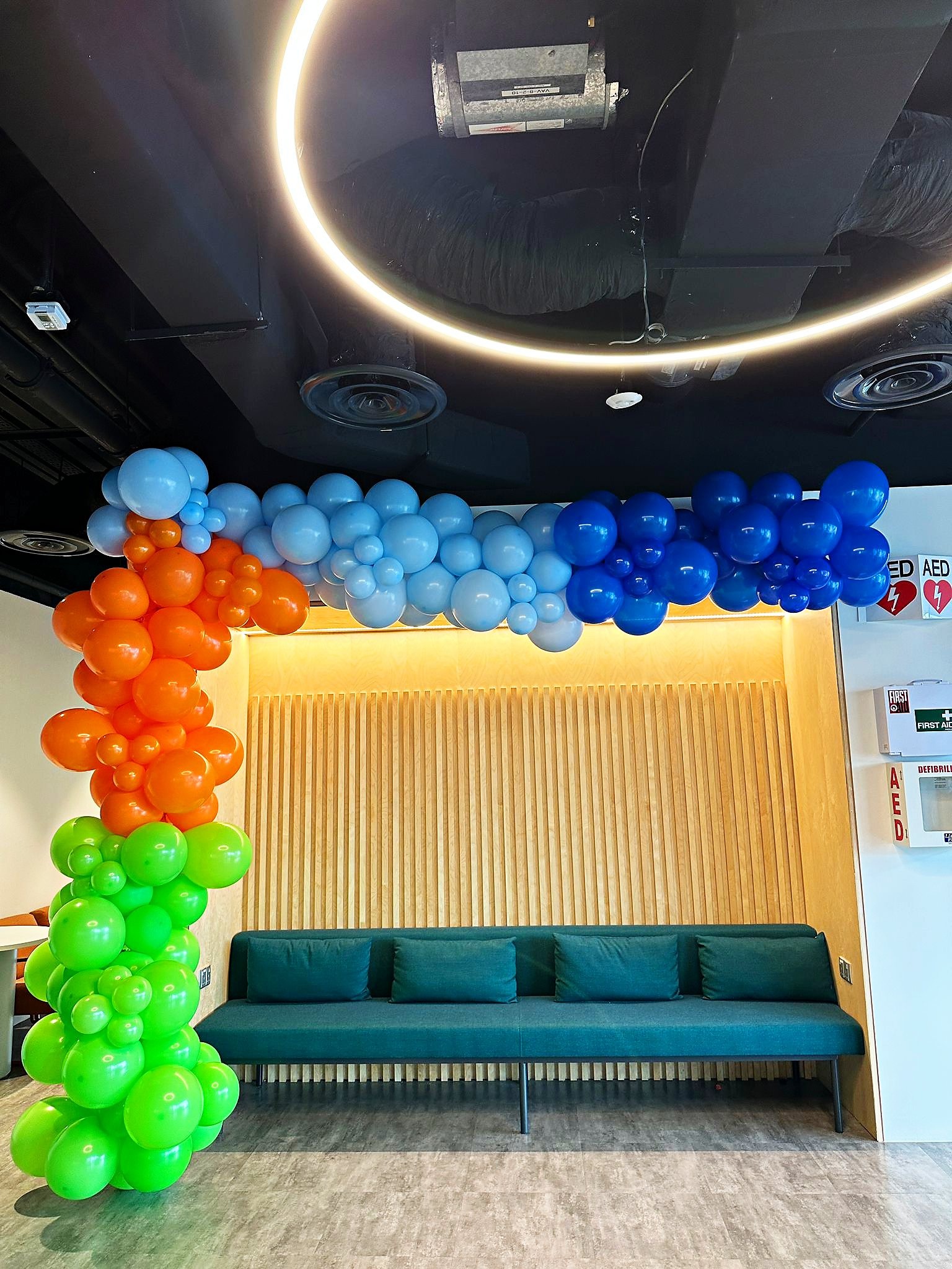 Asymmetric multicolour balloon arch beside lounge seating