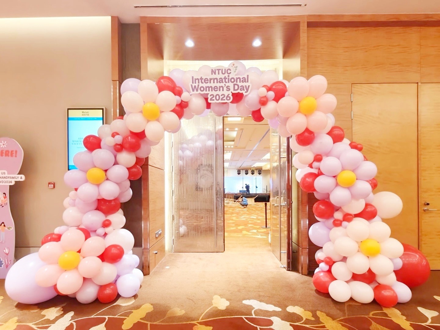 Pink floral balloon arch framing a hotel event entrance
