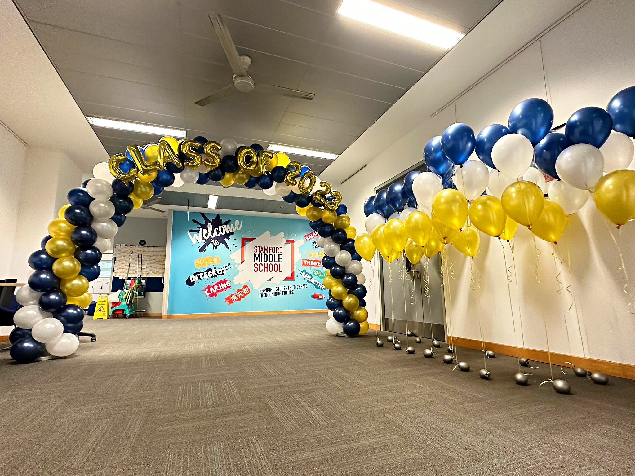 Navy white and gold graduation balloon arch in a corridor