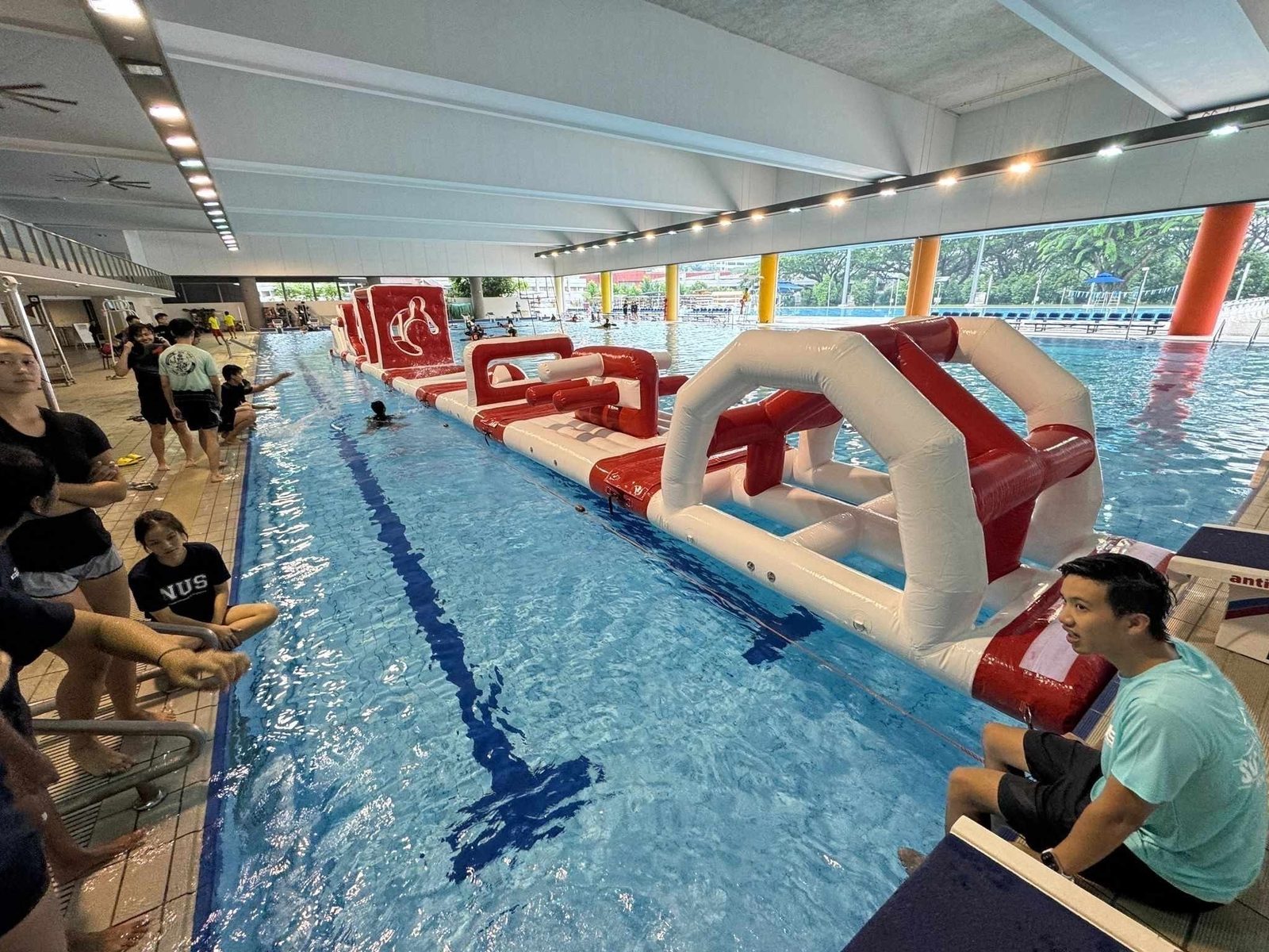 Red and white inflatable water obstacle course in an indoor lap pool Singapore