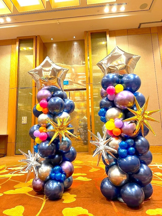 Blue and silver balloon pillars decorated with metallic stars and flowers