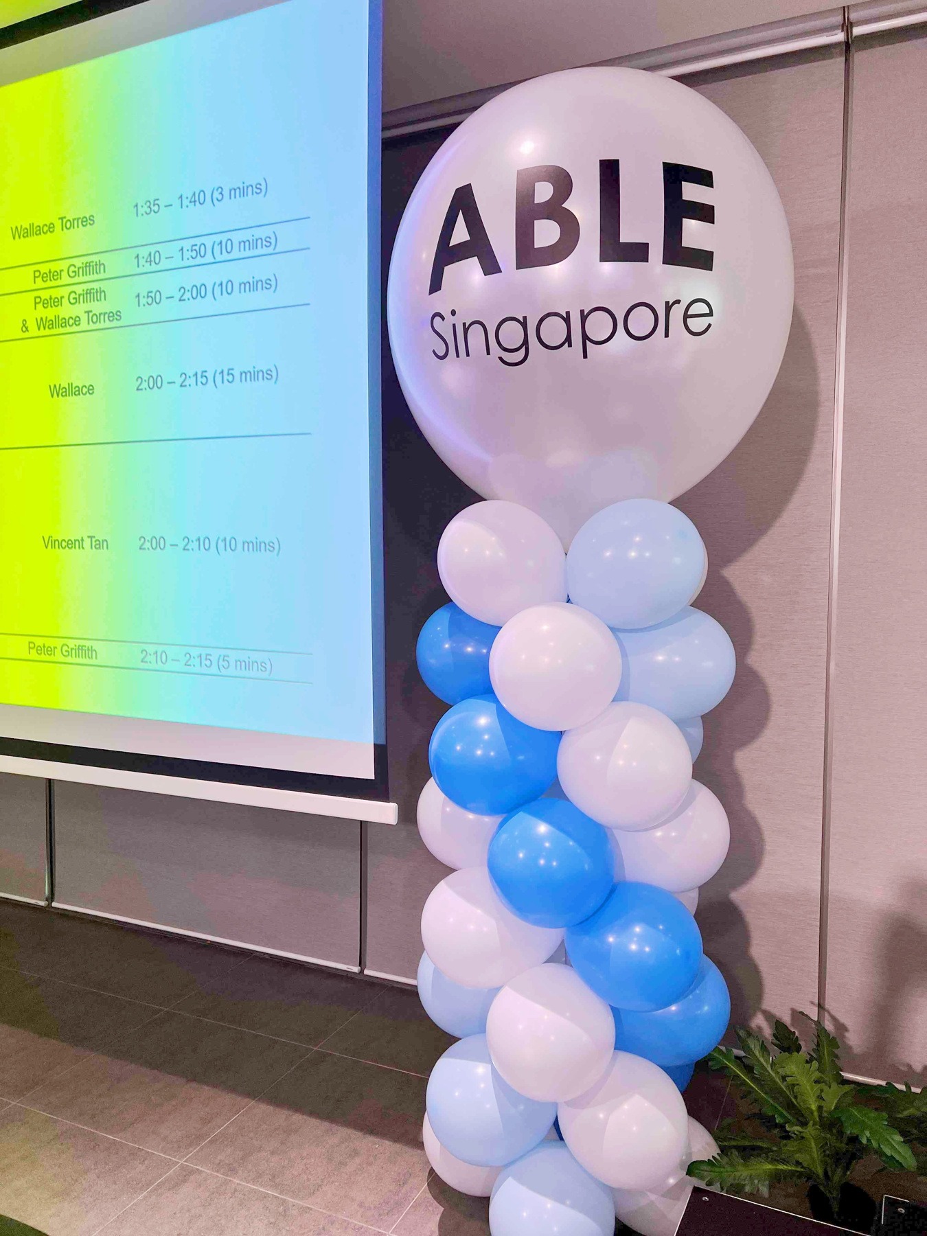 Blue and white balloon pillar with a printed ABLE Singapore topper