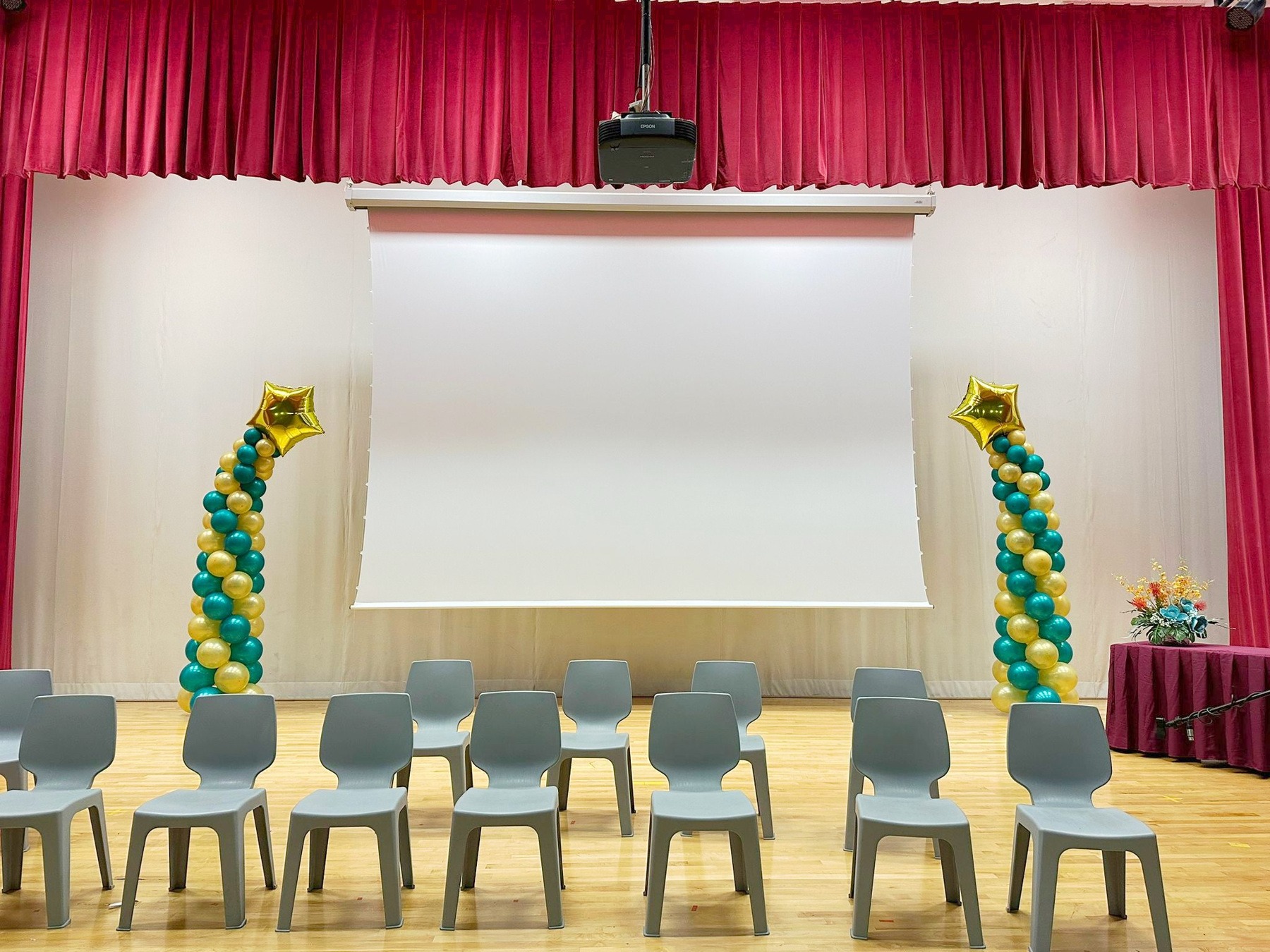 Green and gold shooting-star balloon pillars beside a school stage