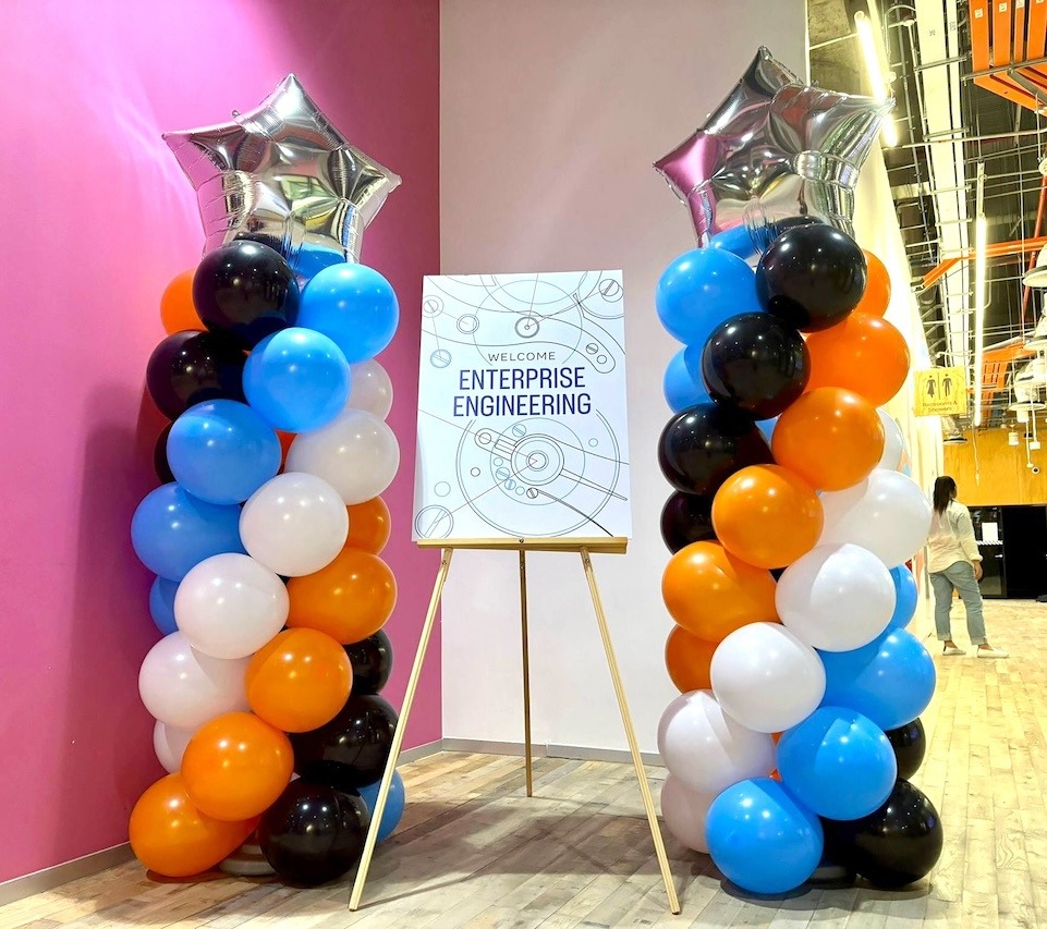 Multicoloured spiral balloon pillars framing an event sign