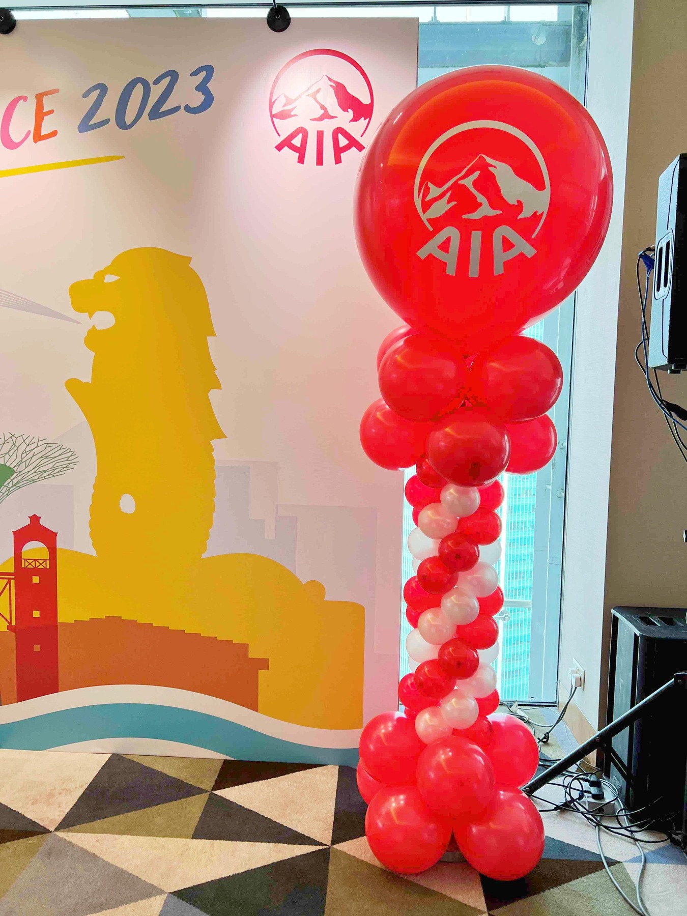 Red and white balloon pillar with a branded corporate topper