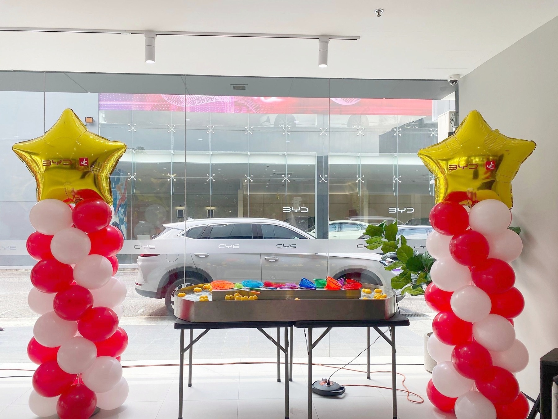 Red and white balloon pillars with gold stars in a showroom