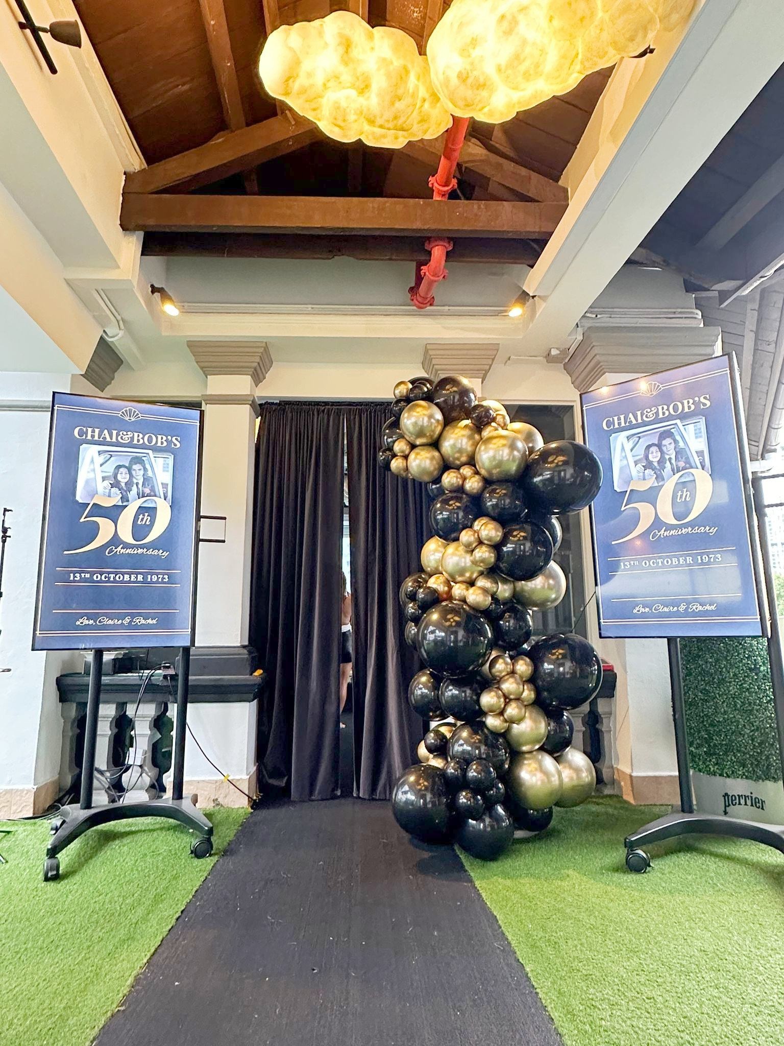Black and gold organic balloon column at an anniversary entrance
