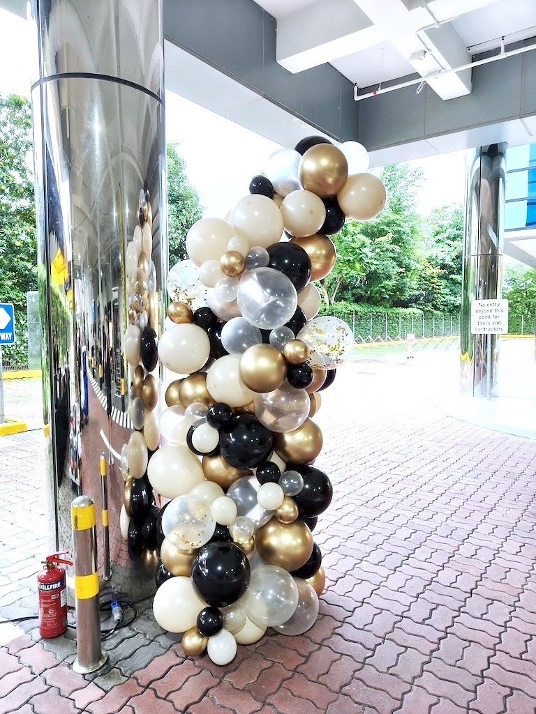 Black white gold and clear balloons beside a glazed entrance