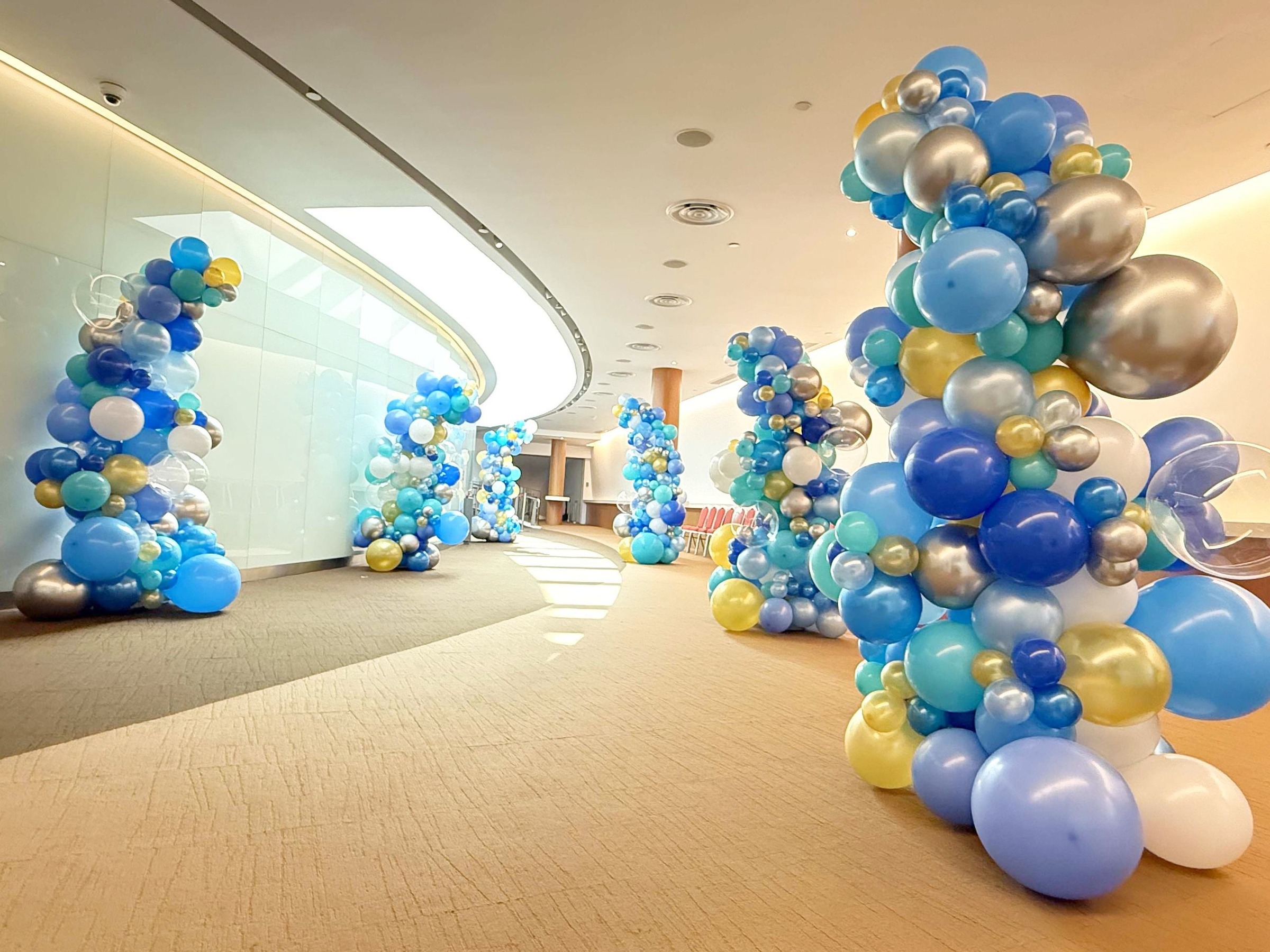 Balloon Colours in blue gold and white repeated along an event corridor