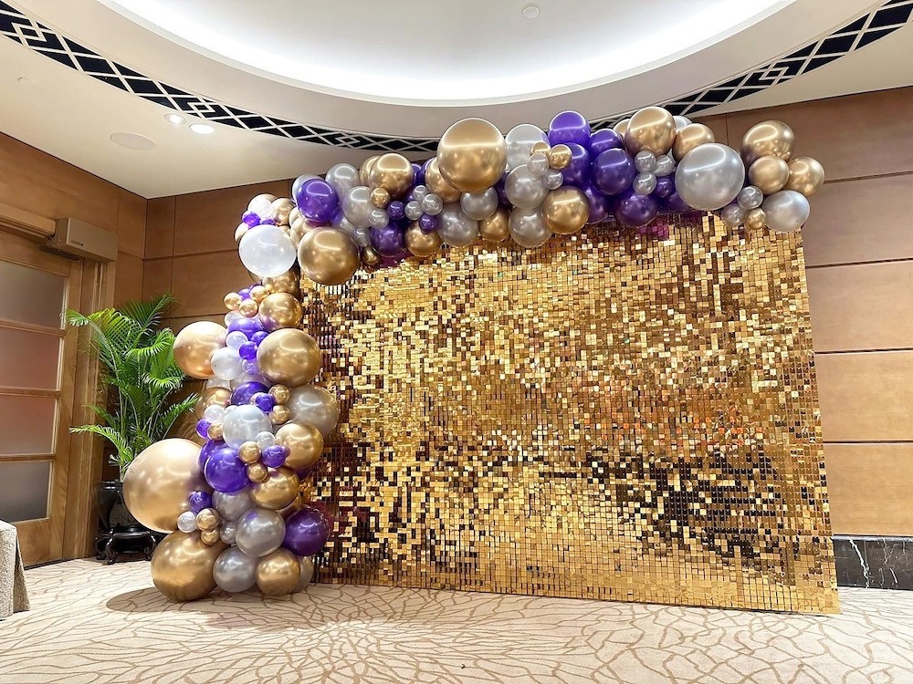 Purple gold and silver garland around a sequin photo wall