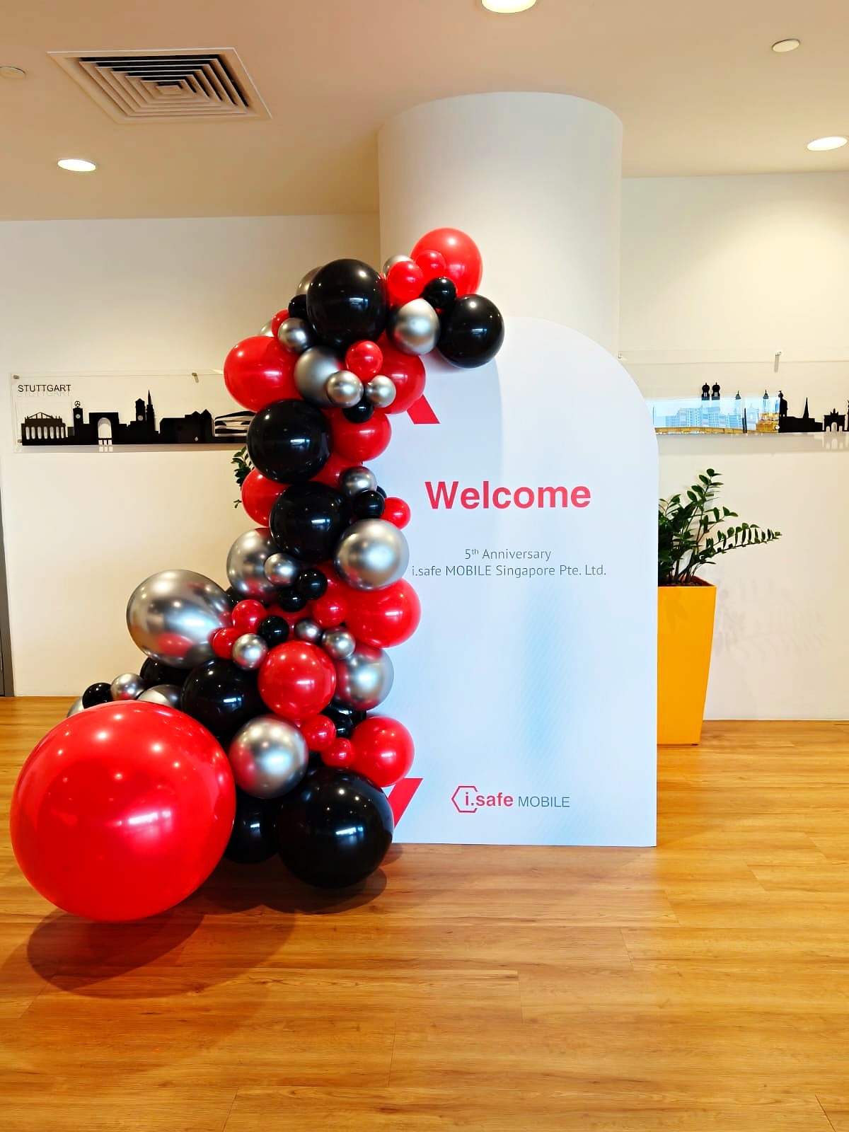 Red black and silver balloons framing a corporate welcome backdrop