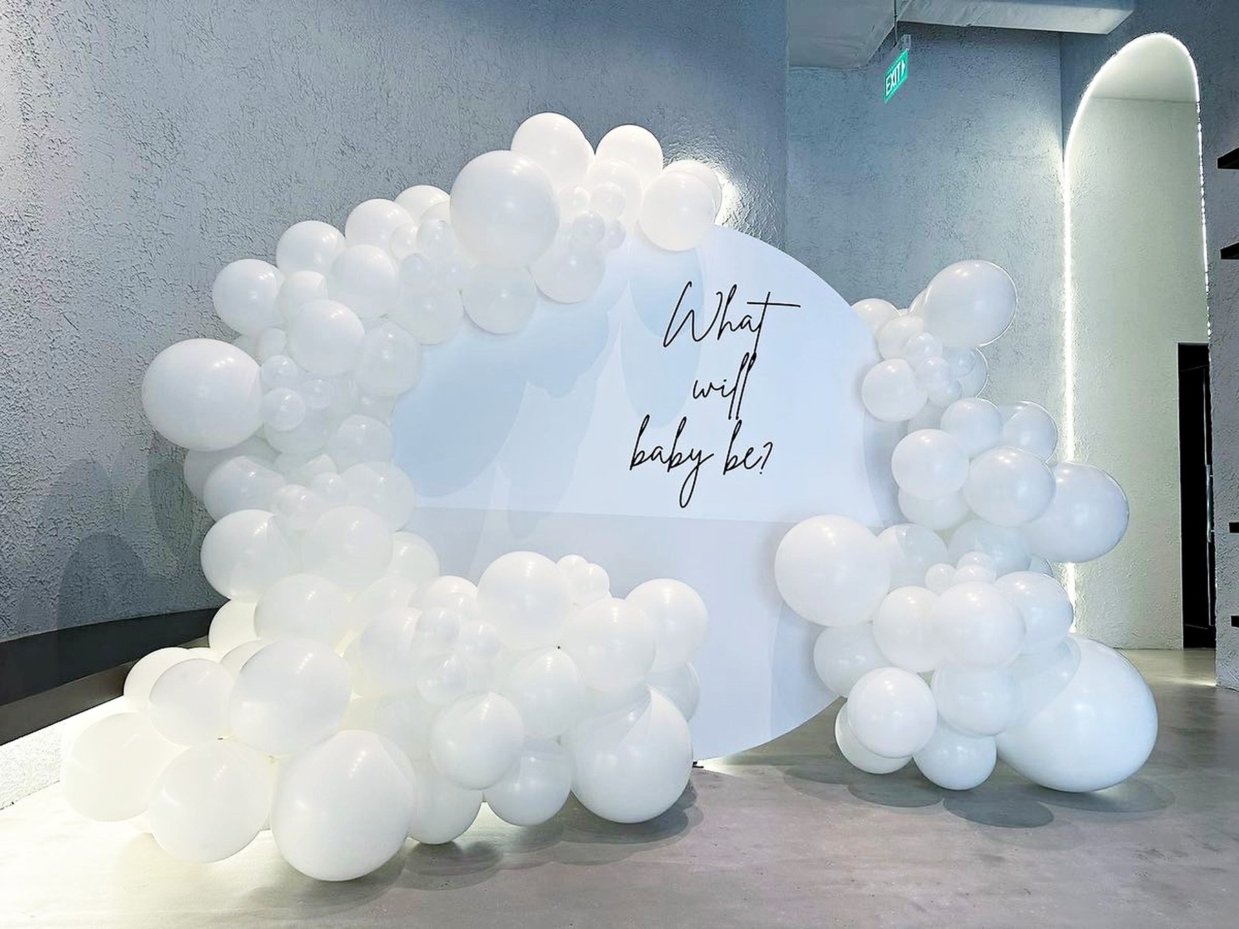 White balloon garland framing a round celebration sign